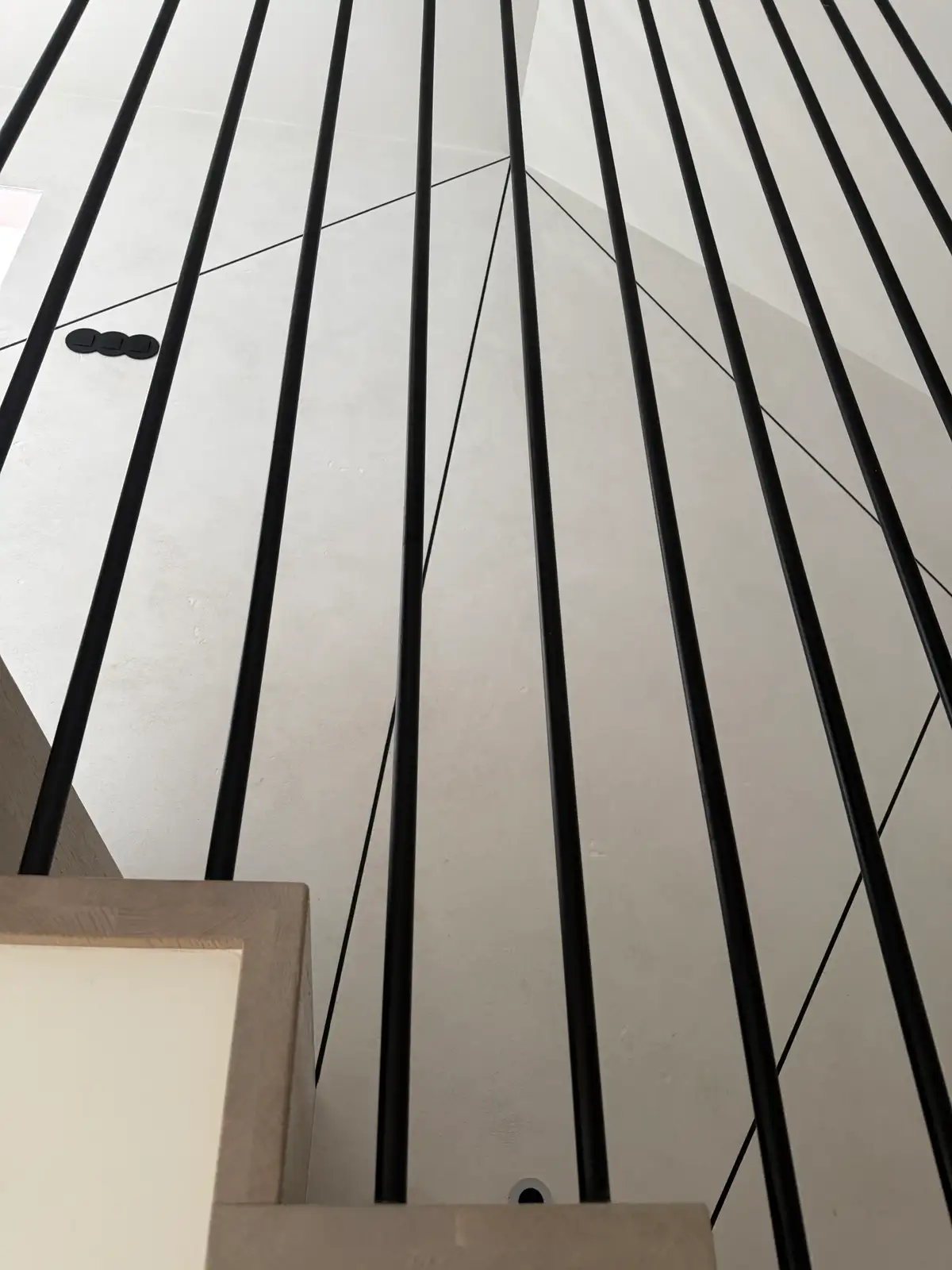 Detal balustrady schodów — czarne pionowe pręty na tle jasnej ściany